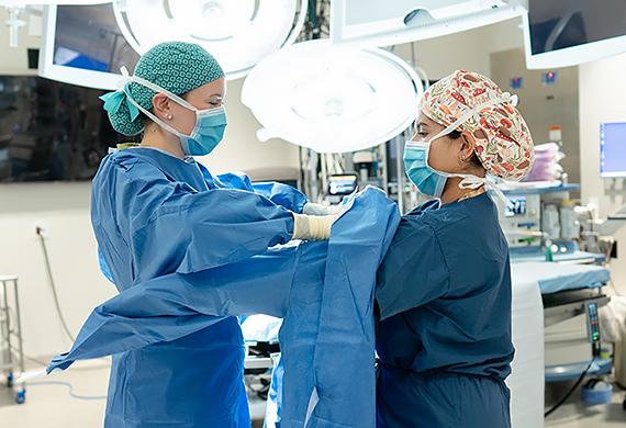 Image of Surgical Physician Assistant at Nuvance Health Danielle Mazzeo helping Marist University Physician Assistant Student Valerie DeLeon prep for work with the surgical team at Vassar Brothers Medical Center in Poughkeepsie, N.Y.