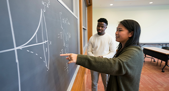 image of students at a chalk board solving math equation