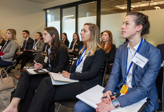 Image of students taking notes at a business presentation.