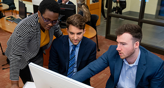 image of three students looking at a computer