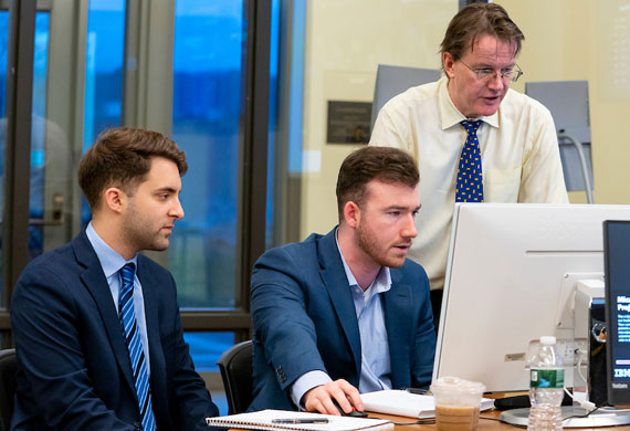 Image of students working with a faculty member in the Investment Center on campus.