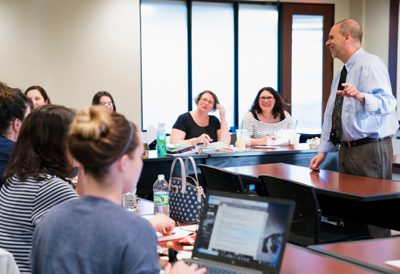 Image of an instructor teaching a group of adult students in a classroom.