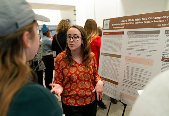 Image of student presenting research to faculty member.