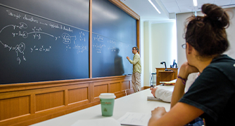 image of professor working on a math equation at chalkboard