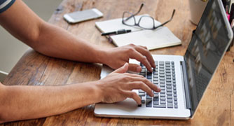 Image of hands typing on a laptop computer.