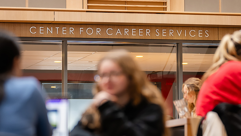 Image of the Center for Career Services sign with students sitting in the Dyson Center.