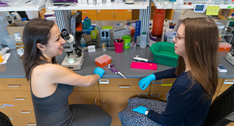 image of two students in a lab conducting experiment