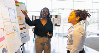 Image of student presenting research to another student