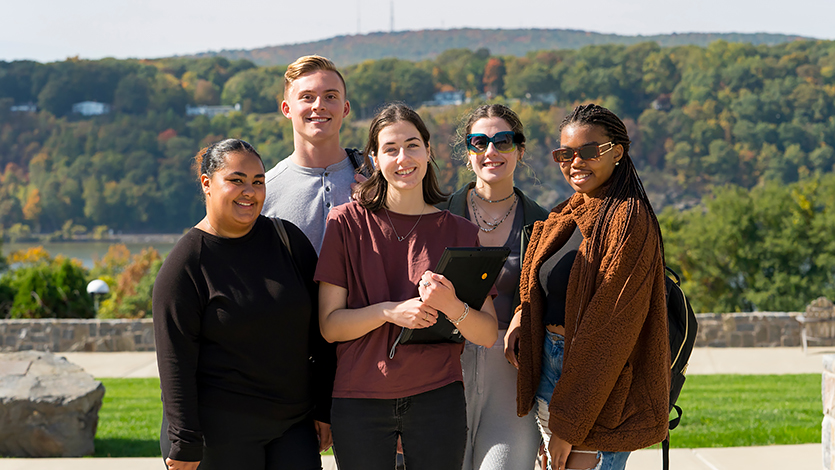 Image of students standing and smiling on campus. 