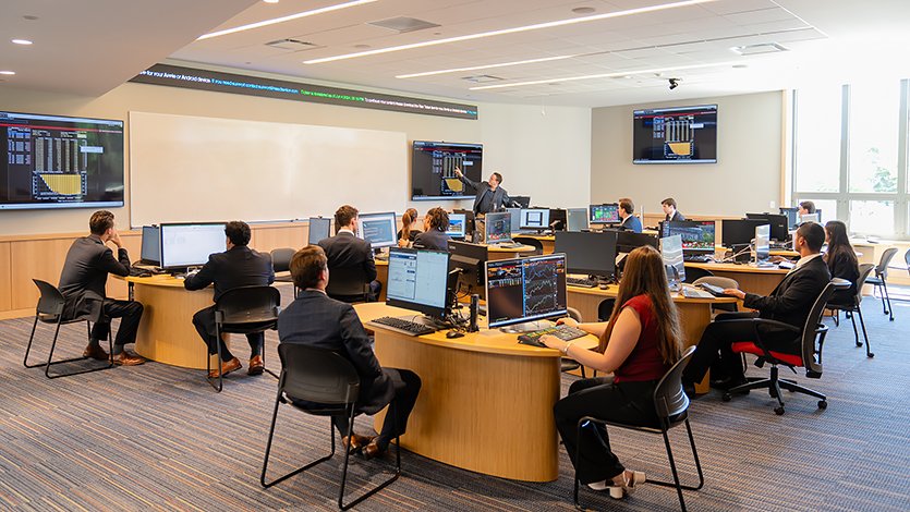 Brian Haughey, Associate Professor of Finance and Director of the Investment Center, discusses financial data with students in the Investment Center on the first floor of the Dyson Center.