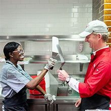 Image of Marist president Kevin Weinman cooking in the dining hall.
